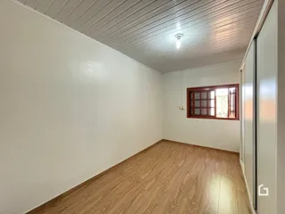 Vista interna de um cômodo com piso de madeira e teto de painel.
