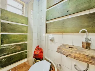 Interior de um banheiro com revestimento de azulejos verdes e brancos.