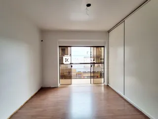 Sala de estar com piso de madeira e porta de vidro que dá para a vista externa.