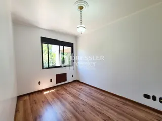 Sala de estar com piso de madeira clara e janela grande.