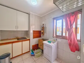 Foto de uma cozinha com armários brancos e revestimento de cerâmica.