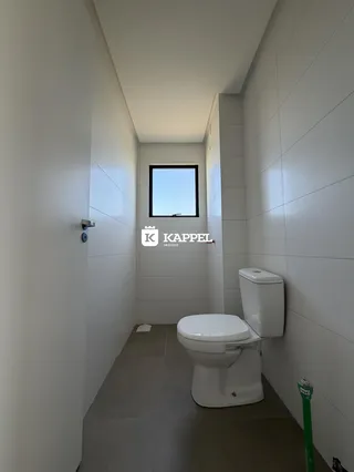 Corredor de banheiro com paredes brancas e um vaso sanitário.