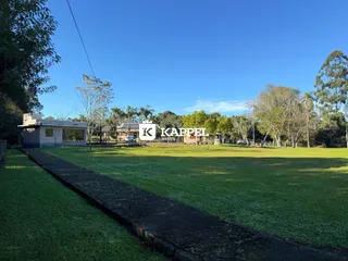 Vista externa do terreno com gramado e caminho de acesso.