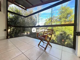 Sala de estar com grande janela oferecendo vista para a vegetação externa.