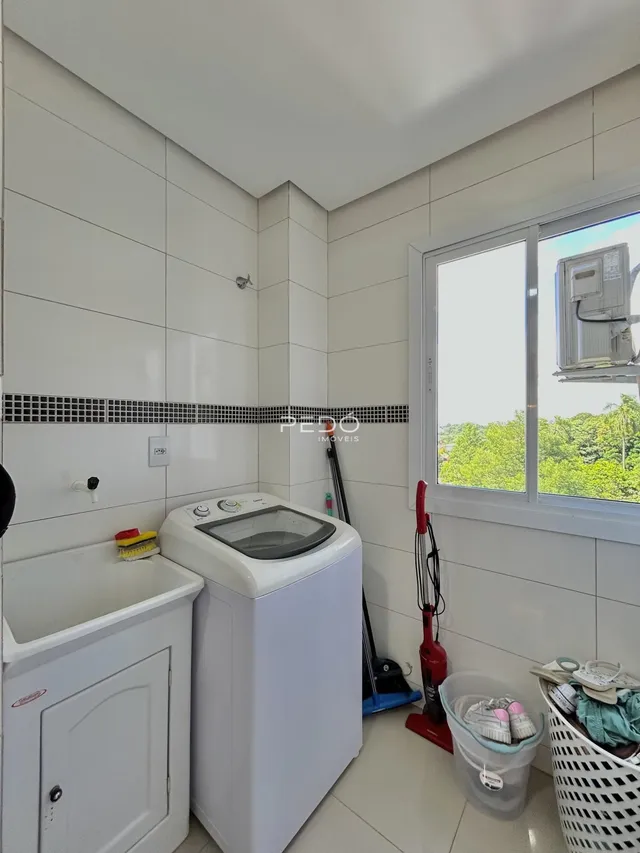 Foto de um ambiente interno com máquina de lavar e pia em cerâmica.