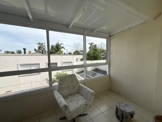 Vista de uma sala com grandes janelas que oferecem uma vista para casas e vegetação.