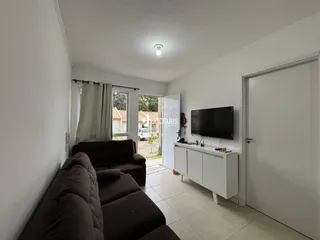 Sala de estar com sofá marrom e paredes brancas.