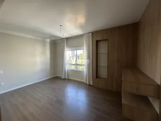 Sala de estar ampla com piso de madeira clara e paredes brancas.