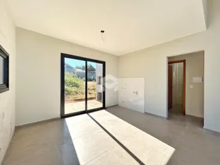 Vista interna de uma sala com porta de vidro abrindo para o exterior.