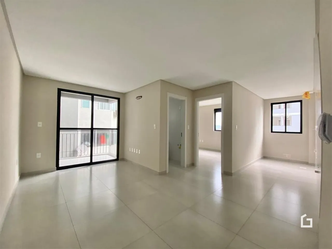 Hall de entrada com piso claro e portas de vidro.