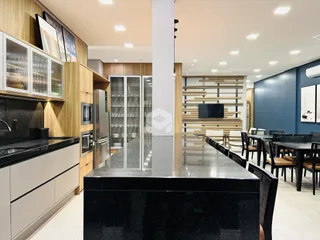 Vista de uma cozinha moderna com ilha e área de jantar em um imóvel no Brasil.