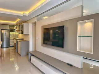 Sala de estar moderna com televisão montada na parede e painel de destaque.