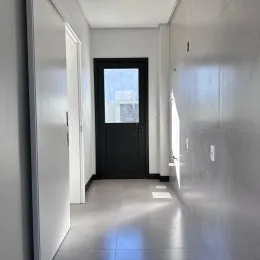 Corredor interno com paredes brancas e piso claro.