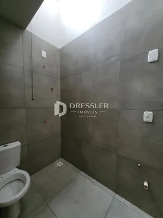 Foto de um ambiente interno com paredes de azulejo cinza e um vaso sanitário.