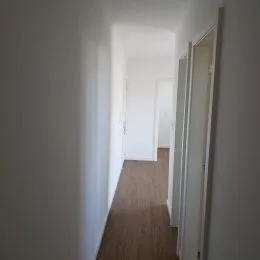 Corredor interno com paredes brancas e piso de madeira.