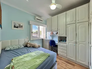 Quarto com cama e armários brancos em ambiente claro.