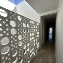 Corredor interno com parede decorativa em relevo.