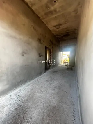 Vista de um corredor interno com paredes de concreto aparente.