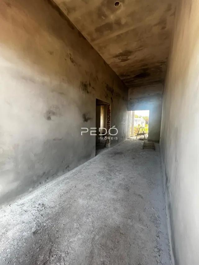 Vista de um corredor interno com paredes de concreto aparente.