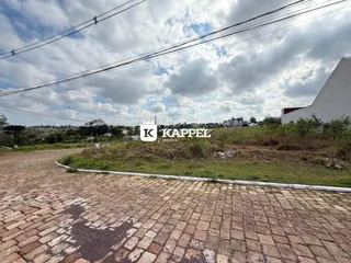 Foto da fachada de uma propriedade com área externa gramada e pavimento de paralelepípedos.