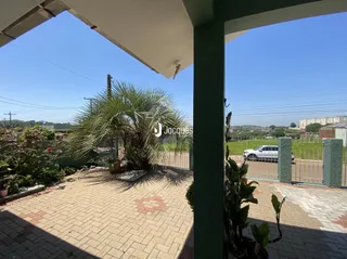 Vista externa de um pátio com piso de tijolos e vegetação.