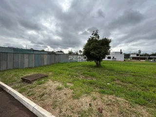 Vista externa de uma propriedade com cerca de metal e gramado.