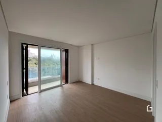 Interior de uma sala com piso de madeira e vista para o exterior.