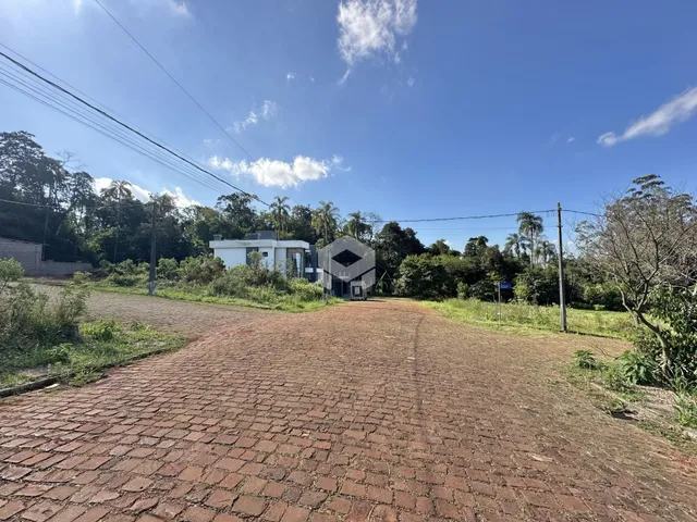 Vista externa da propriedade com paisagem arborizada e pavimento de tijolos.