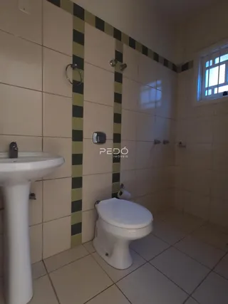 Foto de um banheiro com azulejos brancos e detalhes em verde na parede.