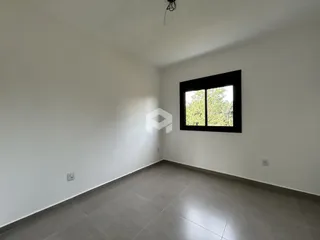 Ambiente interno de uma sala com paredes brancas e piso cinza.