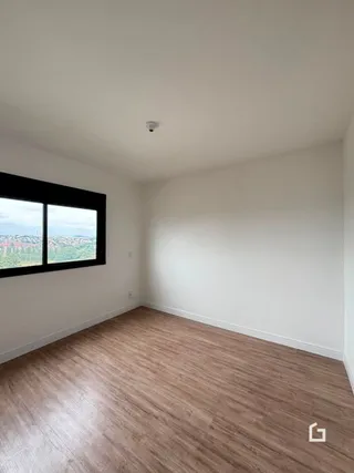 Sala de estar com piso de madeira e janela grande.