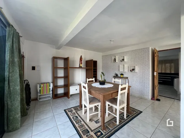 Foto de uma sala de jantar com mesa de madeira e piso cerâmico.