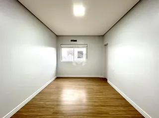 Ambiente interno de uma sala com piso de madeira clara.