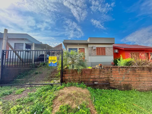 Fachada de casa com muro de tijolos e portão de ferro na propriedade.