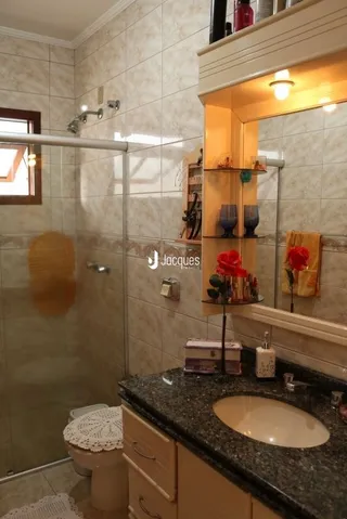 Foto de um banheiro com box de vidro e revestimento cerâmico.