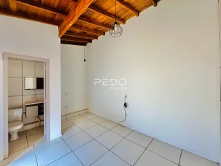 Ambiente interno com piso de cerâmica claro e teto de madeira aparente.