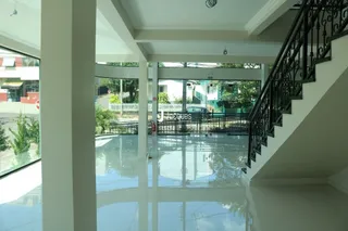 Vista interna de uma área comum com escadaria e grandes janelas.