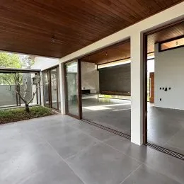 Sala de estar com pé direito alto e piso de porcelanato claro.