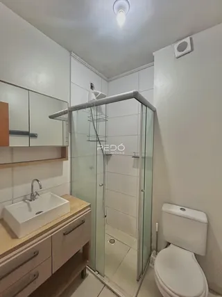 Banheiro com box de vidro e louças brancas.