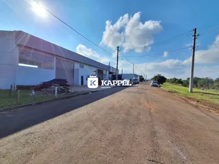 Vista externa de um prédio comercial com garagem e estrada de terra.