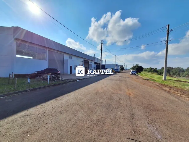 Vista externa de um prédio comercial com garagem e estrada de terra.