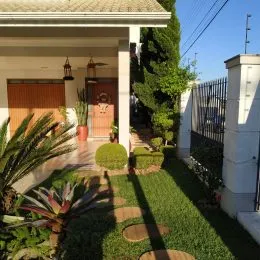 Vista externa da casa com vegetação e jardim.