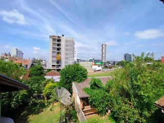 Vista aérea de uma propriedade cercada por vegetação densa e edifícios no fundo.