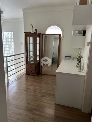 Hall com piso de madeira e espelho grande.