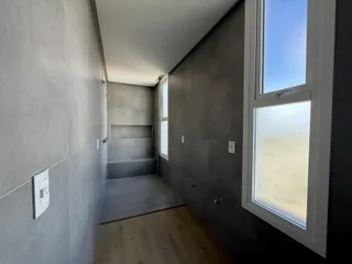 Foto de um corredor interno com paredes cinzas e piso de madeira.