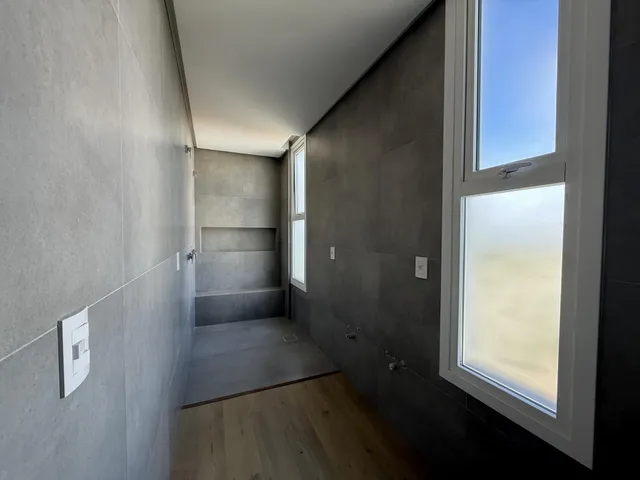 Foto de um corredor interno com paredes cinzas e piso de madeira.