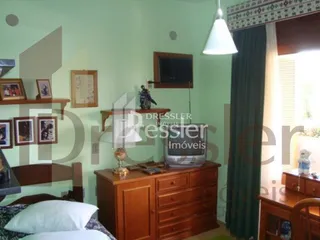 Quarto com cabeceira e cômoda de madeira em uma residência.