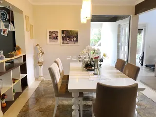 Vista de uma sala de jantar com mesa branca e cadeiras em um imóvel no Brasil.