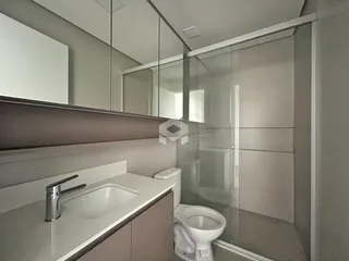 Banheiro com box de vidro e bancada moderna.