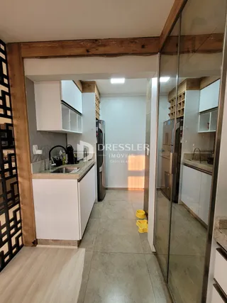 Vista interna de uma cozinha com armários brancos e vigas de madeira.